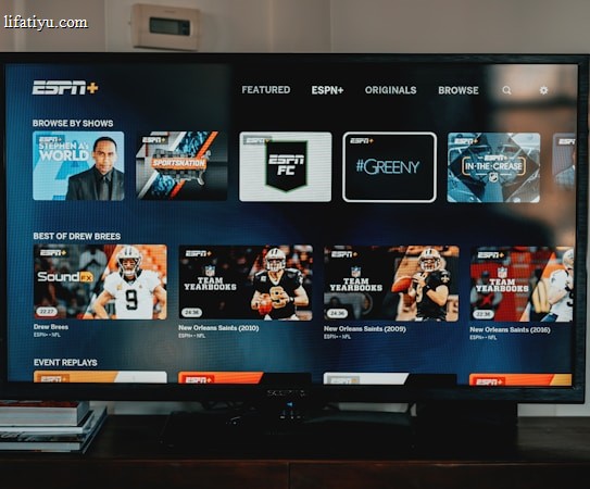 A television screen displaying the ESPN+ streaming interface with various sports-related shows and categories. The screen includes sections such as 'Browse by Shows' and 'Best of Drew Brees' with thumbnails of sports programs featuring athletes in action and analysts.